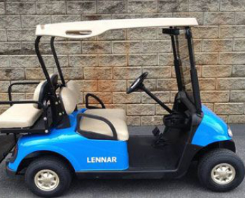 A blue golf cart with beige seats and the word "LENNAR" on the side, parked in front of a brick wall.